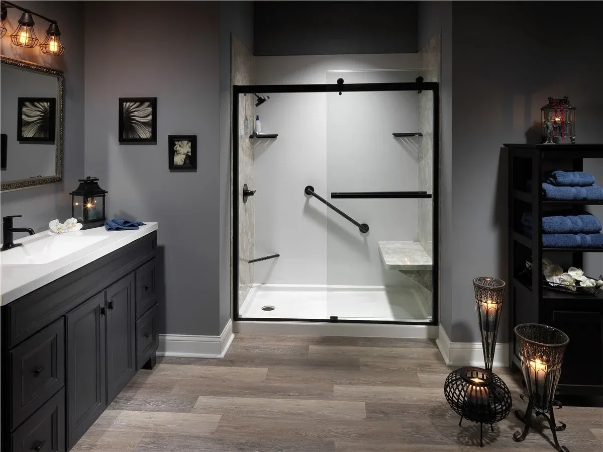 Modern bathroom features dark cabinets, candles, and blue towels. A glass-enclosed shower with grab bars and a bench adds sophistication and comfort.