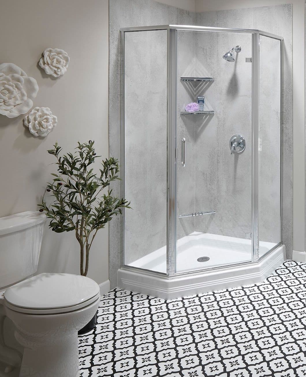 Modern bathroom with an octagonal glass shower, floral wall decor, and patterned black-and-white tile floor. A leafy plant adds a touch of nature.